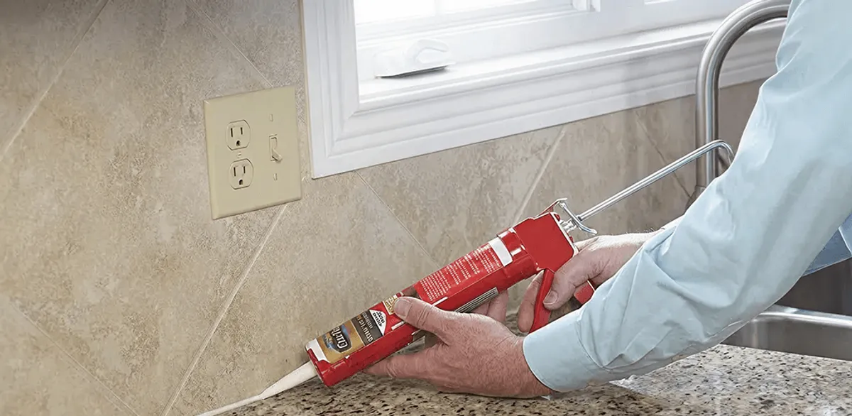 Handyman applying caulk along a kitchen backsplash and countertop seam in Yonkers, NY